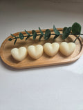 Four heart-shaped wax melts on a wooden tray with eucalyptus