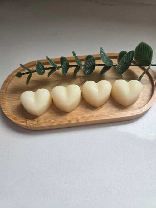 Four heart-shaped wax melts on a wooden tray with eucalyptus