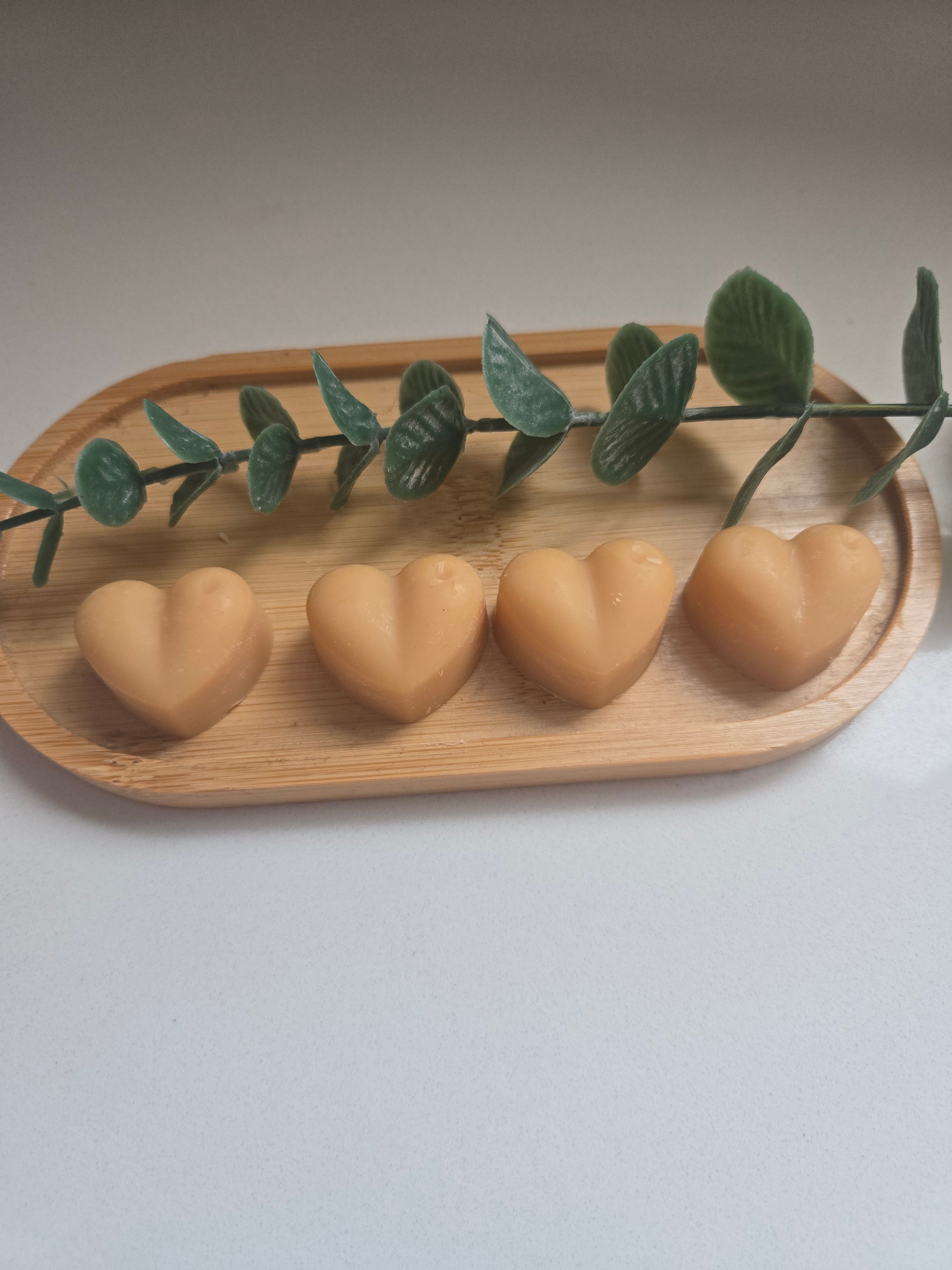 Four amber/golden heart-shaped wax melts on a wooden tray - colours may vary