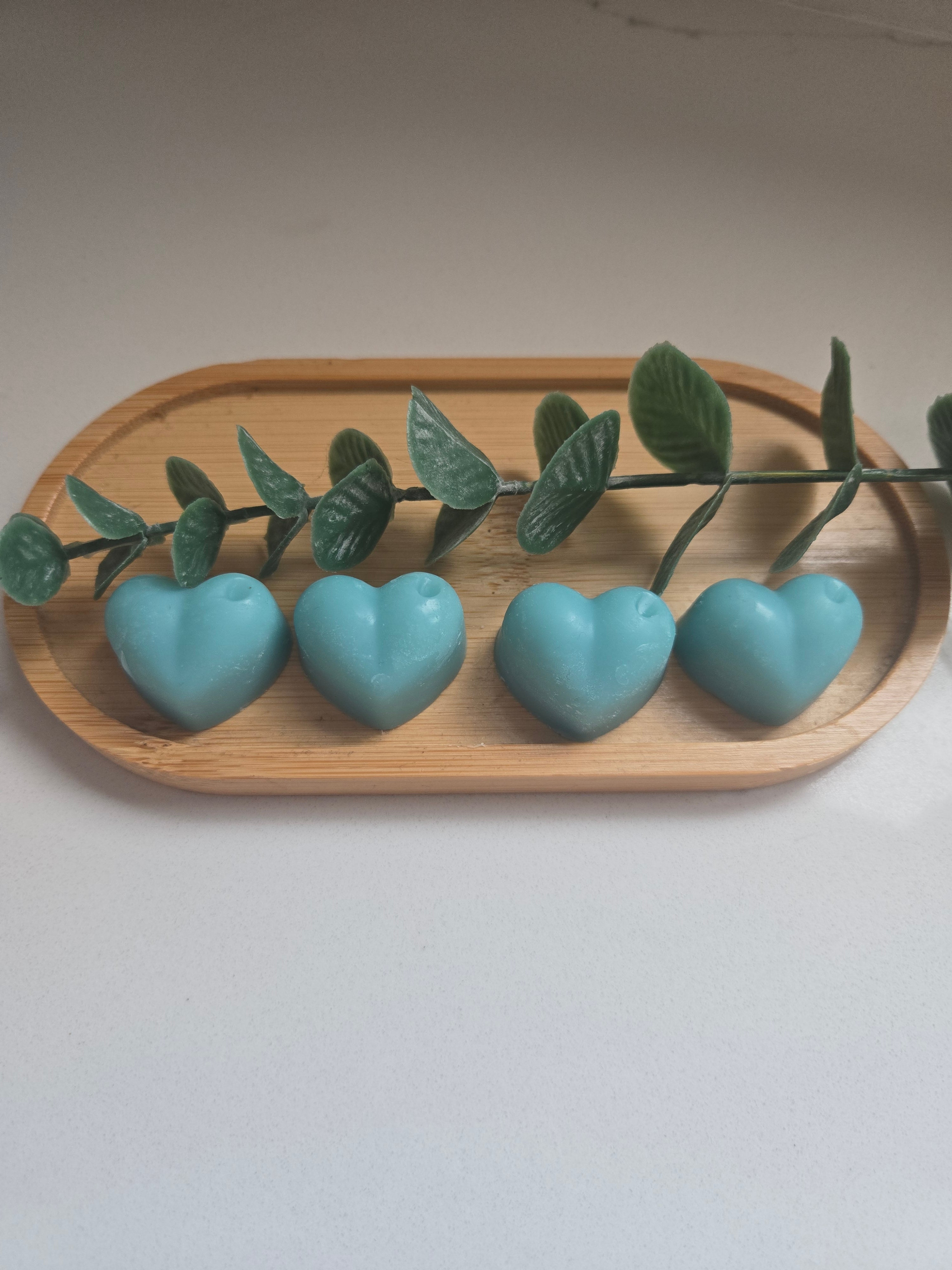 Four teal heart-shaped wax melts on a wooden tray - colours may vary