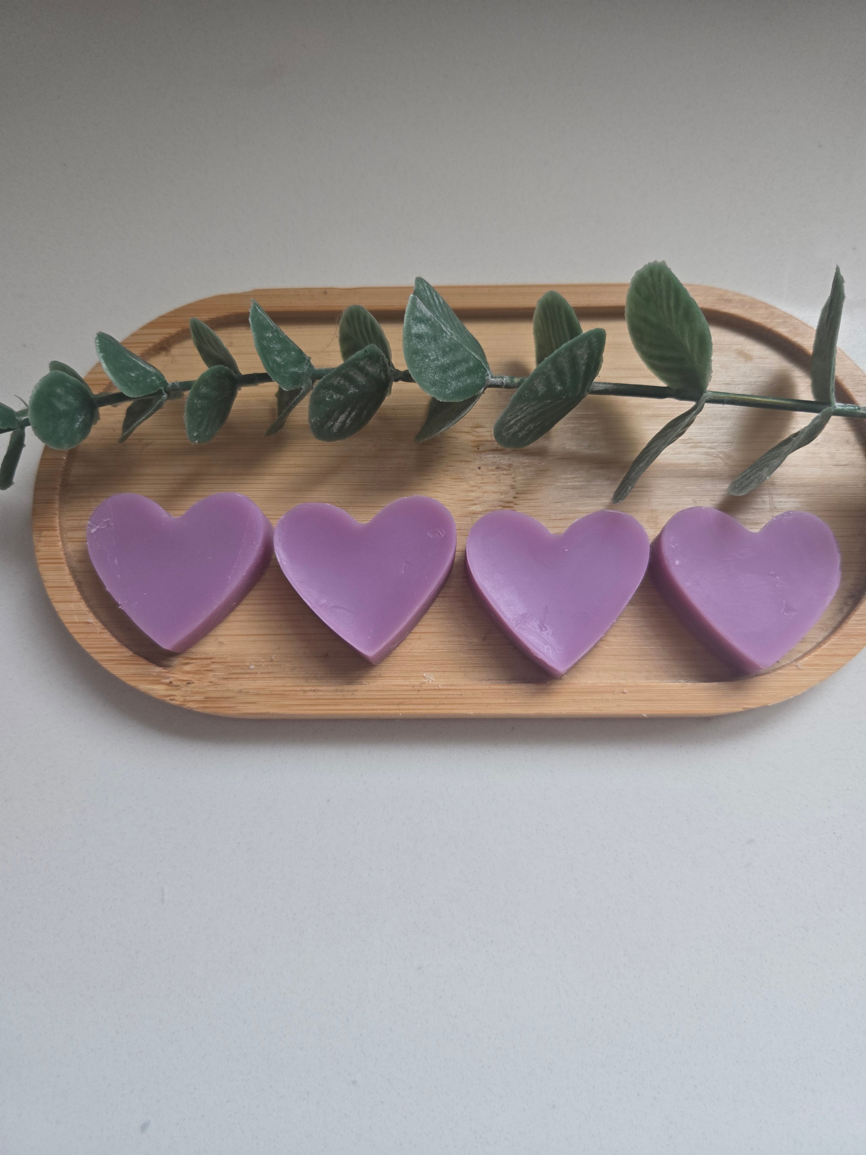 Four purple heart-shaped wax melts on a wooden tray - colours may vary